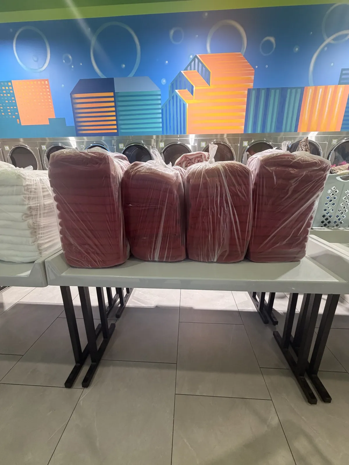 Folded red linens sealed in clear bags on a WASH MAXX folding table