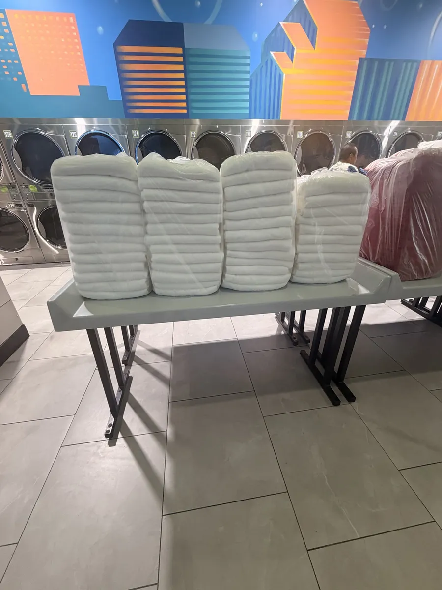 Stacks of folded white towels bagged in front of WASH MAXX dryers